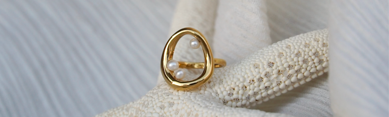 Gold and Pearl Naiad Ring placed on a starfish
