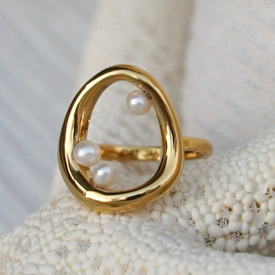 Gold and Pearl Naiad Ring placed on a starfish