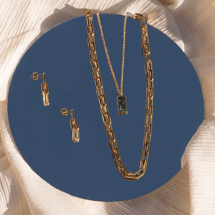 Gold Sol Chain Link Earrings, Sol Link Necklace and Abalone Pendant on mirror with sky reflecting behind it