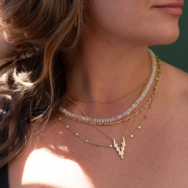 Woman wearing 4 gold chains: Nebula Necklace, Mini After Glow Pendant, Anchor Chain, Thin Chain and 14K Gold and Opal One of a kind necklace.