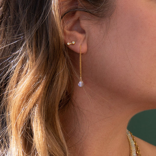 Woman wearing the Small Stardust Studs in her second piercing and the 14K Gold Dew Drop Threader Earring in her primary peircing in Moonstone 