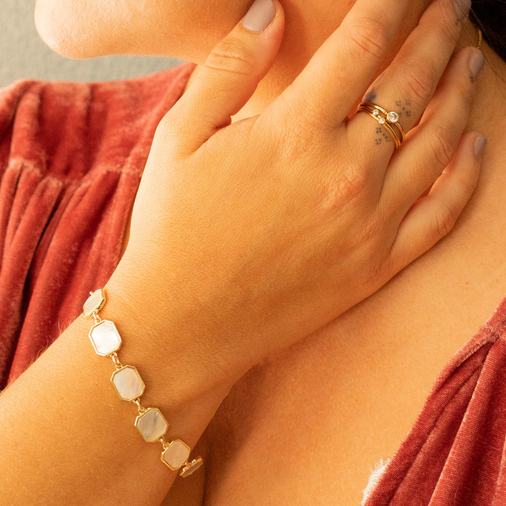 Woman wearing Mother of Pearl Bracelet and 3 white topaz rings