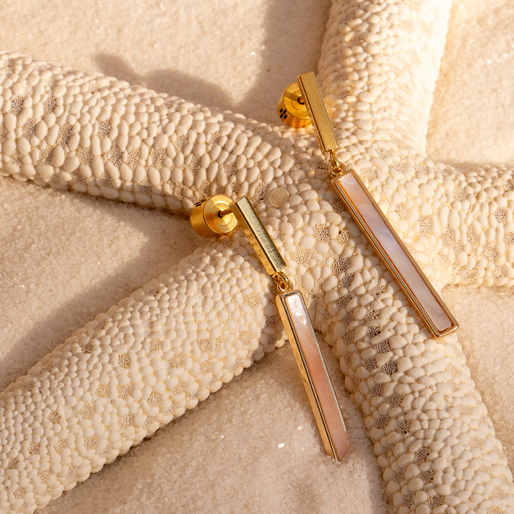 Mother of Pearl Bar Drop Studs laying on a starfish