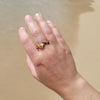 Hand wearing a gold ring on a sandy background