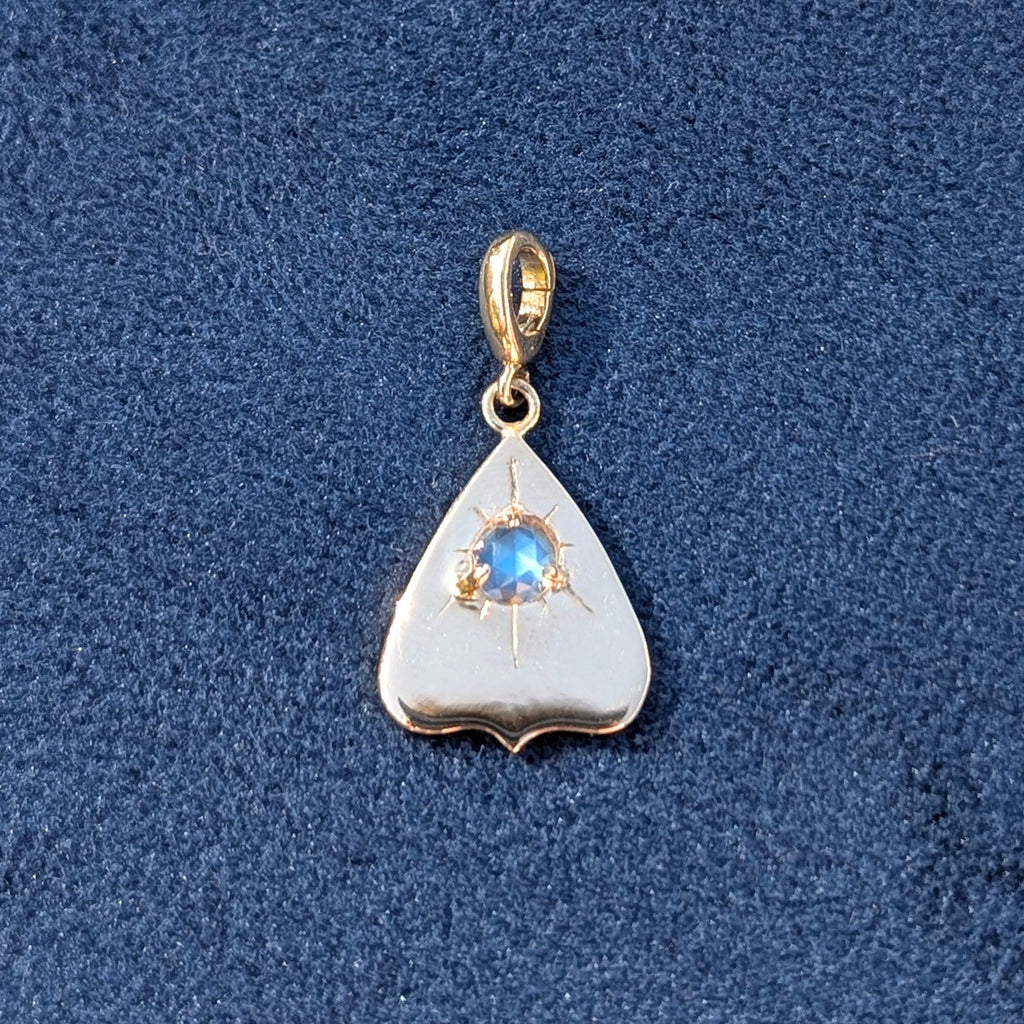 Gold pendant with a rainbow moonstone gemstone on a blue textured background