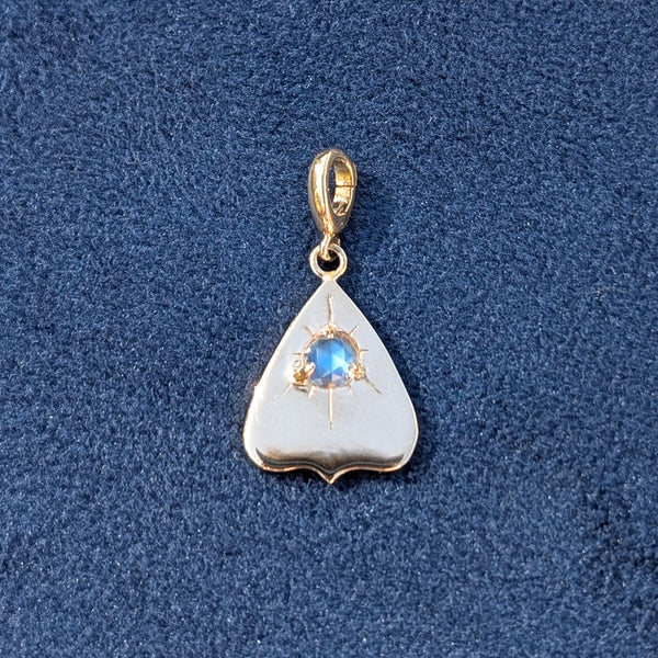 Gold pendant with a rainbow moonstone gemstone on a blue textured background