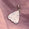 Gold and diamond constellation planchette charm pendant on a pink fabric background