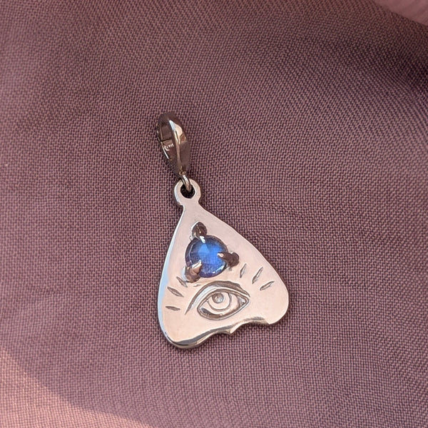 Gold pendant with rainbow moonstone gemstone on a purple fabric background