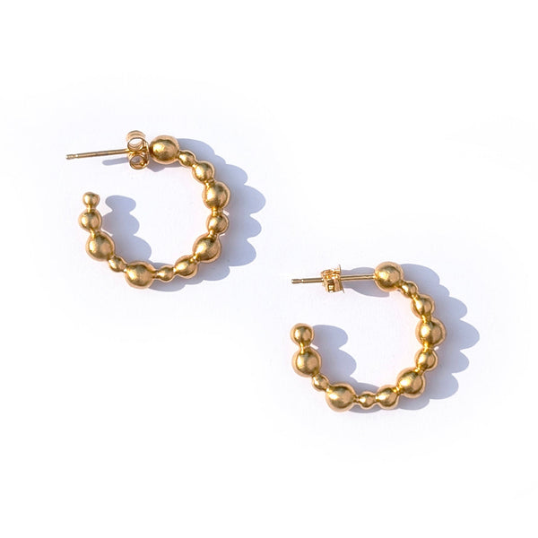 Gold hoop earrings with bead detailing on a white background