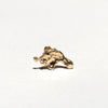 A small, rough, textured gold piece, resembling a miniature gold nugget or abstract gold chunk, displayed on a clean white surface with a soft shadow.