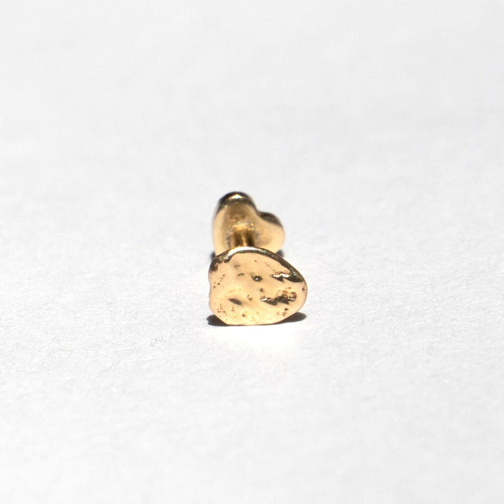 A small gold stud earring with a textured, hammered finish, photographed on a plain white background.