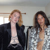 Band IconaPop standing in a room, showcasing fashion outfits. on the left she wears a black velvet blazer and tSilver Cat Janiga Petal Hoops.