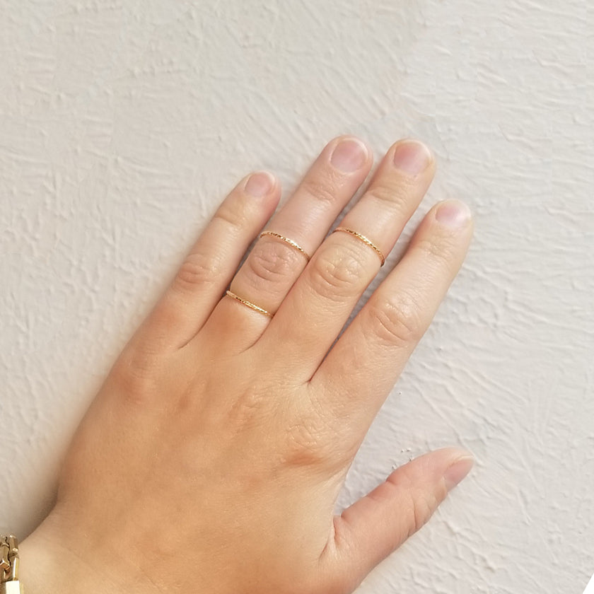 Hand wearing gold spellbound rings on separate fingers