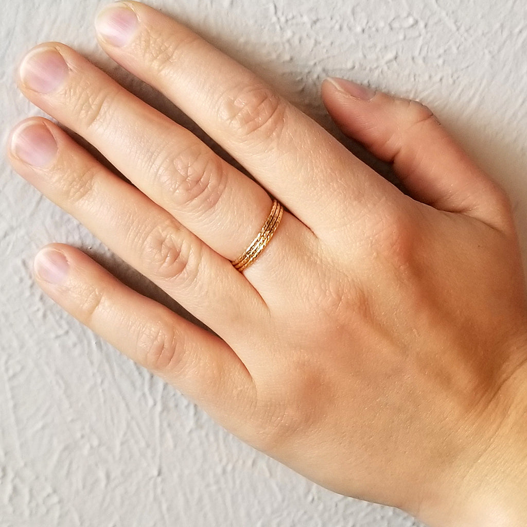 Hand wearing gold spellbound rings on one finger