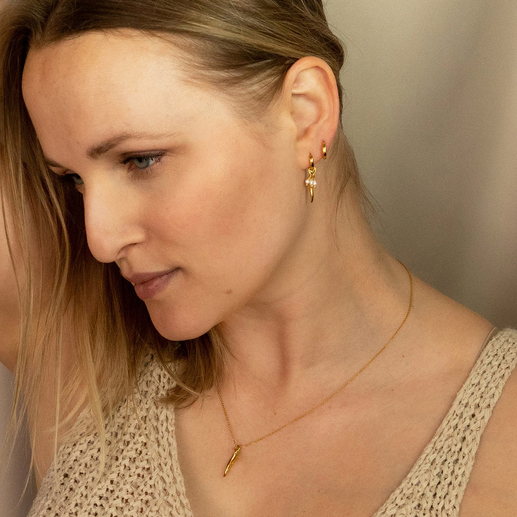 Woman wearing Gold Drift Pearl Huggies and Ebb Pendant