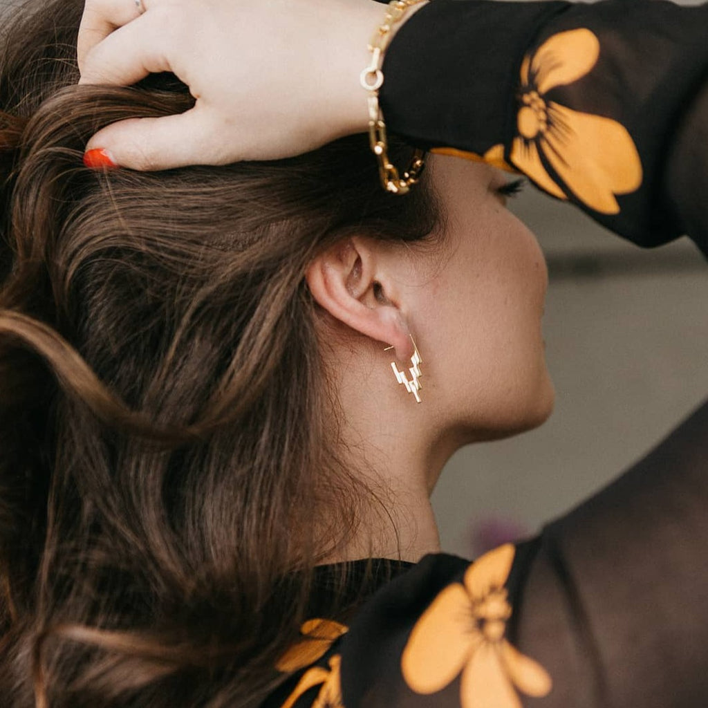 Brunette woman wearing Gold After Glow Huggies and Sol Link Bracelet