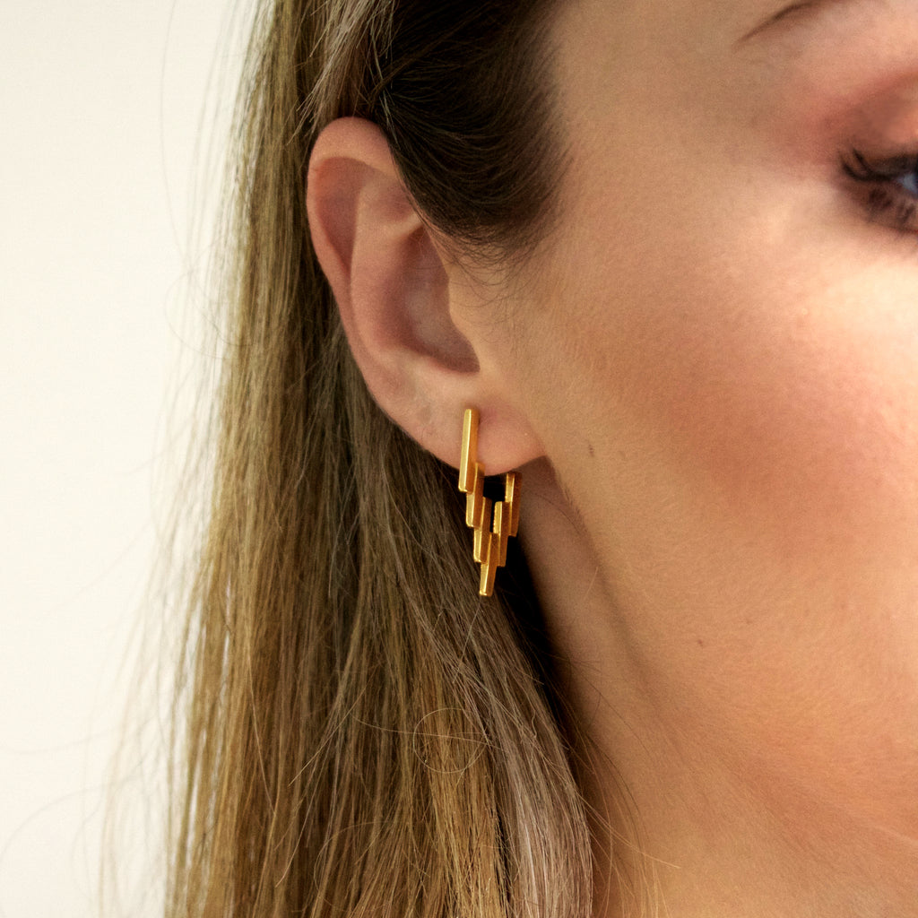 Close up of woman wearing Gold After Glow Huggies