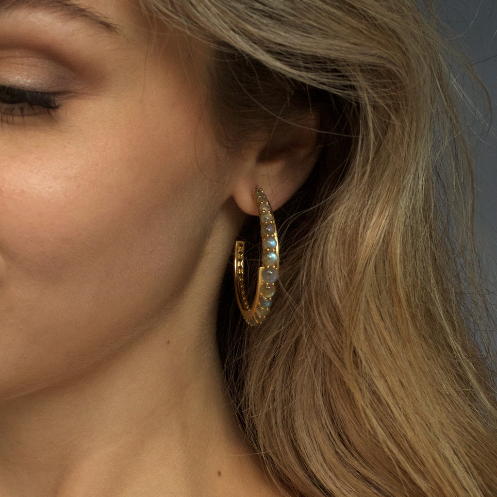 Close up  of woman wearing the gold andromeda hoops in labradorite