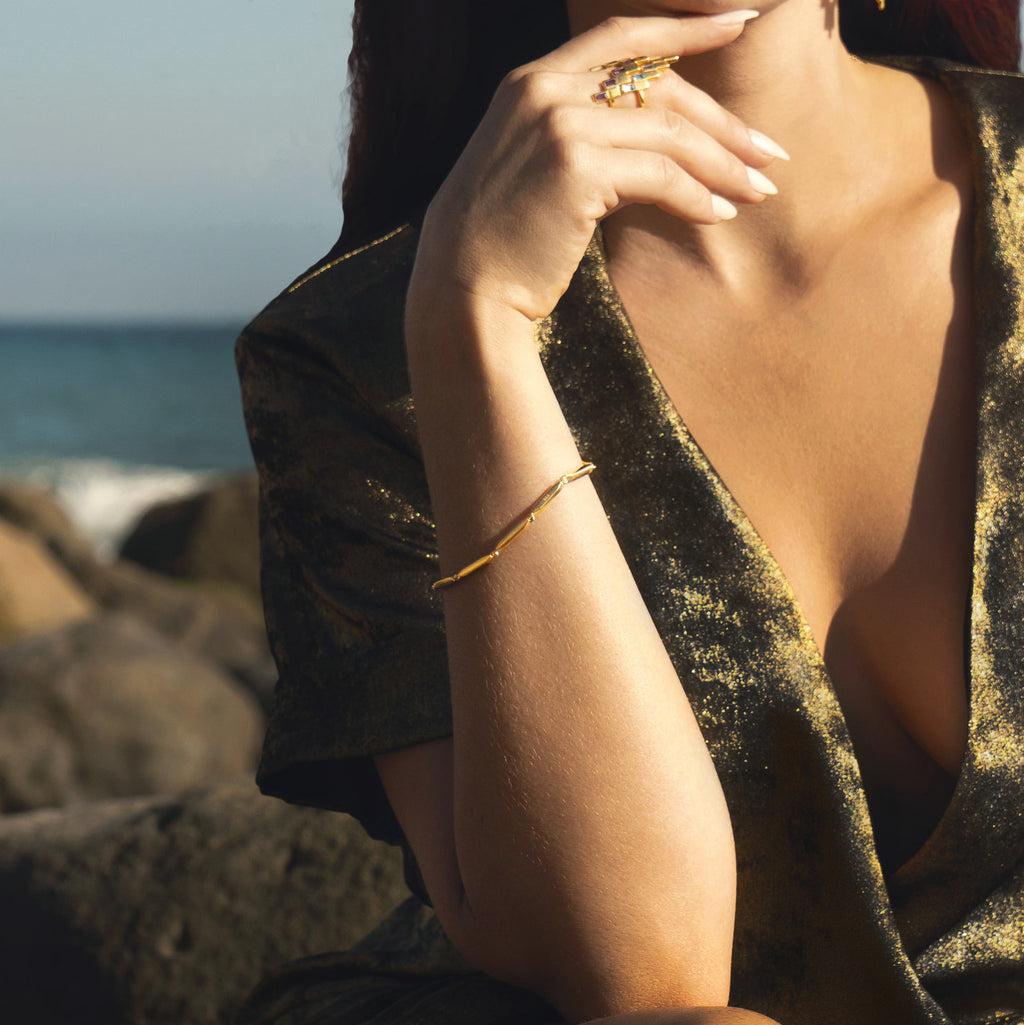 Woman wearing gold Sol Bracelet and After glow rings