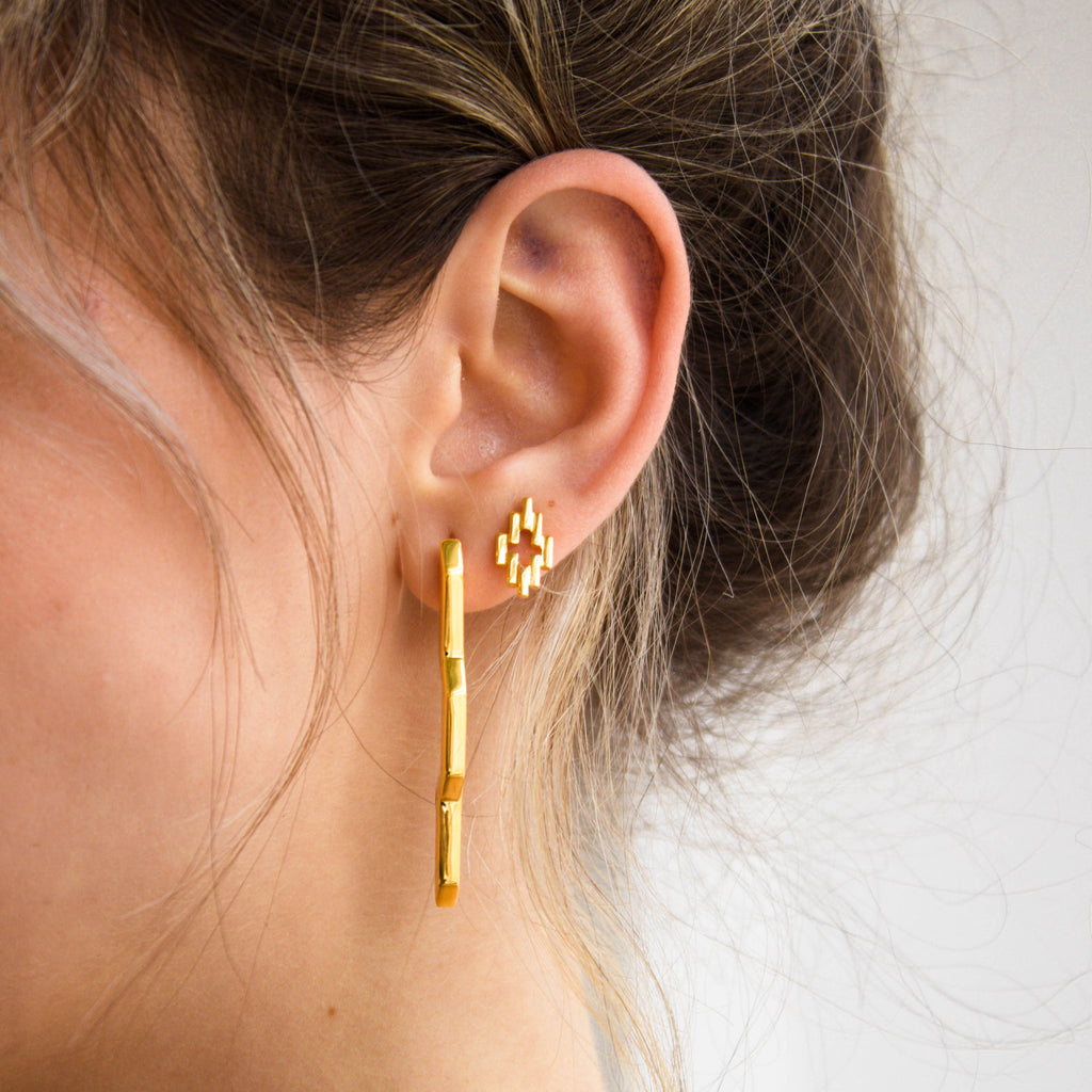 Close up of Small Gold Solar Flare earrings and gold aura studs being worn layered on one ear